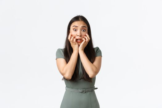 Small business owners, women entrepreneurs concept. Terrified asian woman in dress looking in panic, shivering and stare scared at horrible scene, standing alarmed over white background