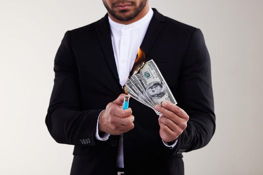 Ive got money to burn. Studio shot of an unrecognisable businessman burning a banknote against a white background.