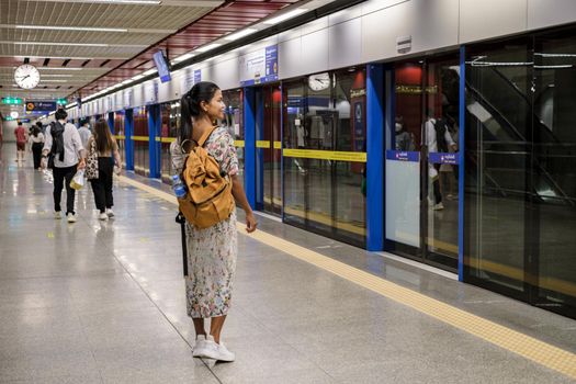 Asian woman tourist waiting for skytrain at railway station platform in the city Bangkok Thailand