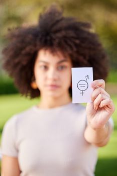 The purpose of protest to provoke a response. a young woman holding a card in protest in a park.