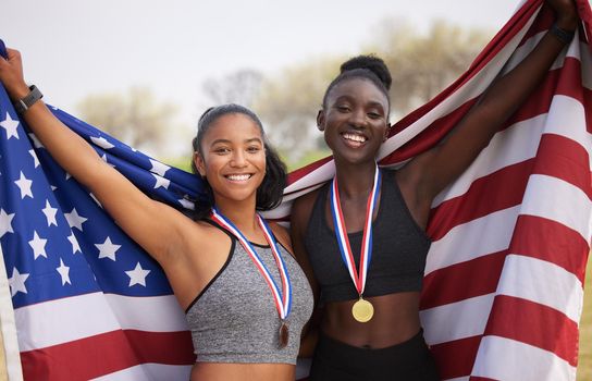 Its an honor to represent your country. Cropped portrait of two attractive young female athletes celebrating their countrys victory.