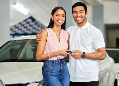 Dont just dream about it, drive it. a young couple showing their car keys at a car dealership.