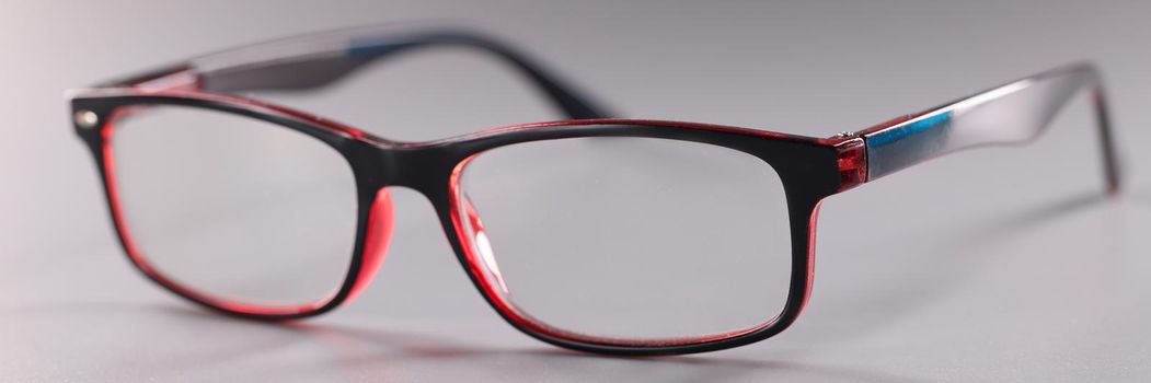 Fashionable plastic glasses red-black on gray background