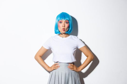 Portrait of beautiful korean girl pouting coquettish, looking at camera silly, standing in blue wig and party costume for halloween