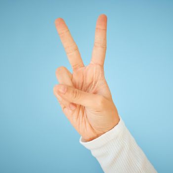 Dream a little dream of peace. an unrecognizable woman showing the peace sign against a blue background.