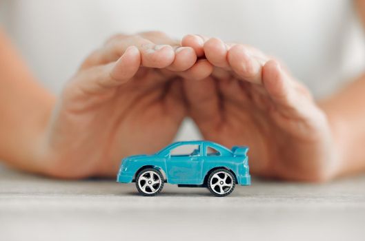 Take care of your car. a unrecognizable female covering a toy car with his hands at home.