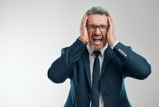 The markets are crashing. Studio portrait of a mature businessman screaming against a white background.