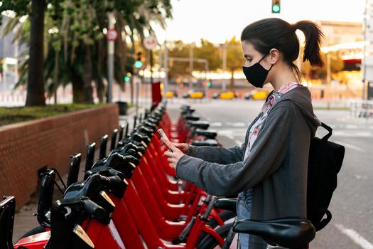 woman with mask renting a bike with the phone
