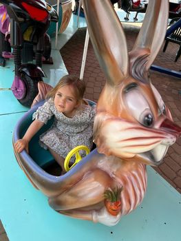 Little girl sits on a carousel in a park