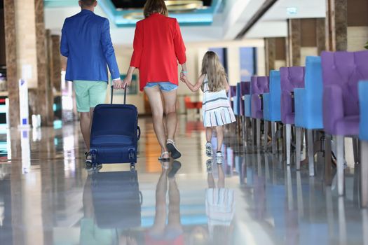 Rear view of family with suitcase while walking in airport or hotel