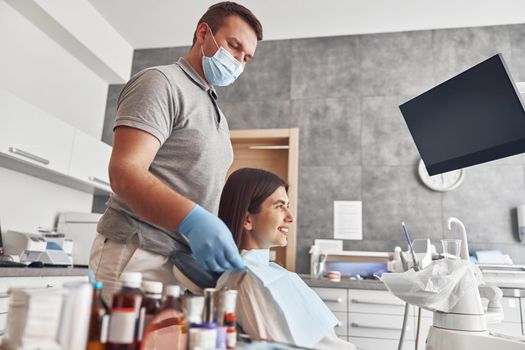 Confident male doctor is preparing young woman to dental survey