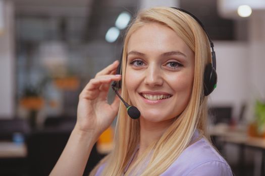 Friendly customer support operator with headset working at call center