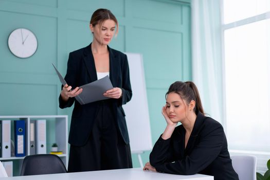 Young women leaders are checking financial statements from paper documents. Two female confident business worker dressed black suit in office checking financial document