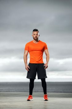 Athletic man doing fitness exercises on the ocean beach