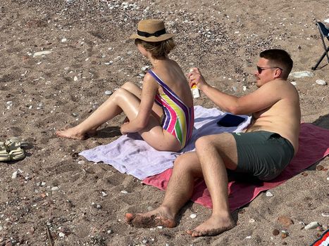 Man rubbing suntan lotion on woman back