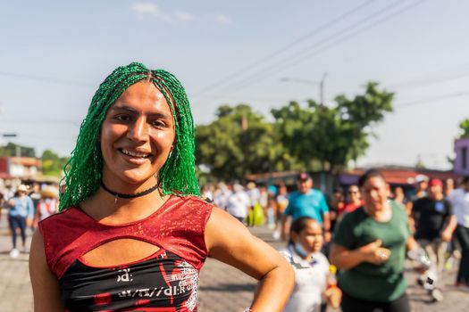 Young Latino gay with green braids outdoors smiling at camera