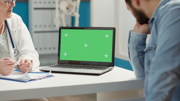 Young adult and medic using laptop with greenscreen at checkup visit