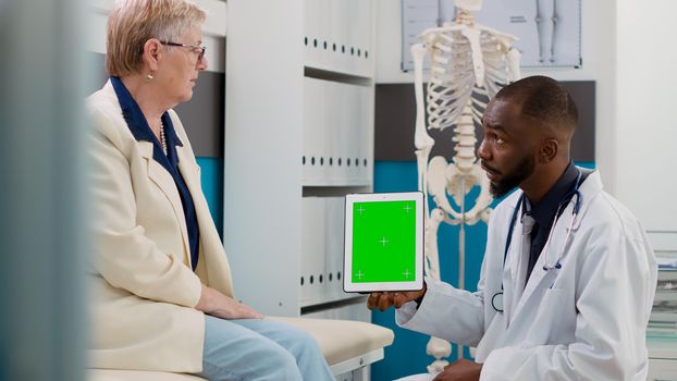 Male physician holding digital tablet with greenscreen in cabinet