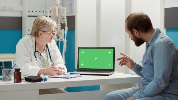 Physician and patient analyzing greenscreen template on laptop