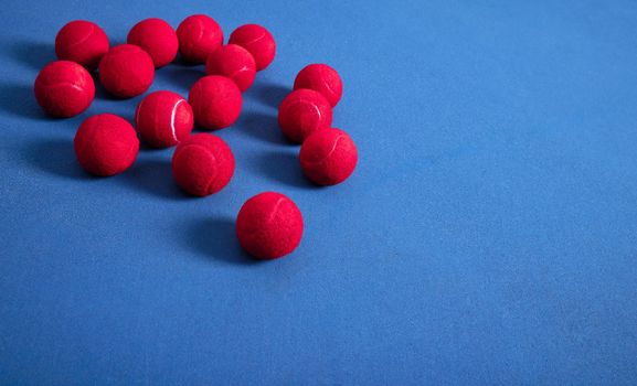 Tennis is a sport that is popular throughout the world. multiple tennis balls lying on a blue tennis court.