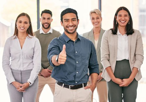 Youre making the right decision with this team. a handsome young businessman standing in the office with his colleagues and showing a thumbs up.