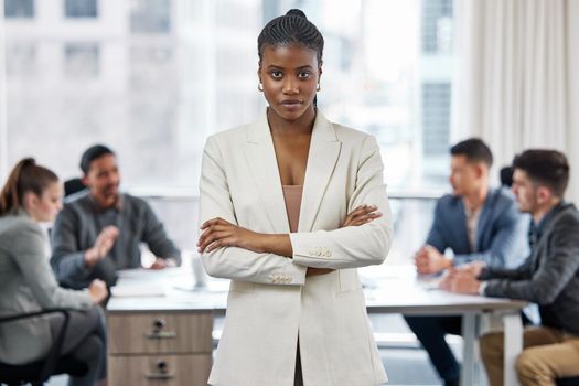 I run the show over here. a young businesswoman standing with her arms crossed in a meeting at work.