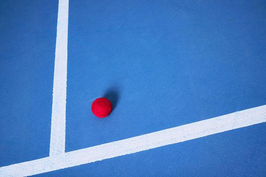 The ball is round, the game is long. one red tennis ball lying on a blue tennis court.