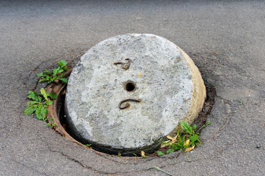 An old sewer manhole with an open concrete cover