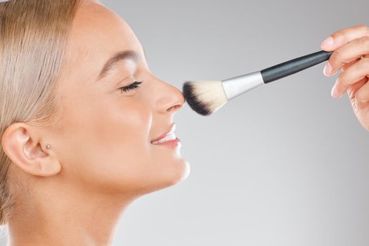 There is no instant miracle cure. an attractive young woman using a makeup brush against a studio background.