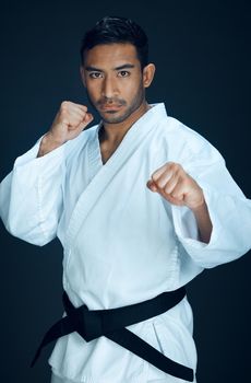 Karateka. Cropped portrait of a handsome young male martial artist practicing karate in studio against a dark background.
