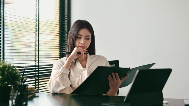 Thoughtful millennial businesswoman reading bank financial loan investment agreement at her workplace