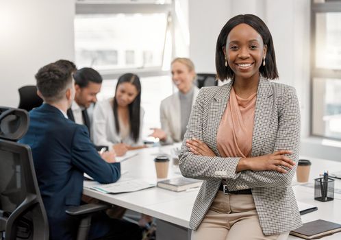 Every new day presents a new opportunity of becoming successful. a young businesswoman standing with her arms crossed in the boardroom with her colleagues in the background.