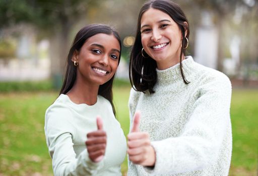 Good luck with your next exam. two young women showing thumbs up outside at college.