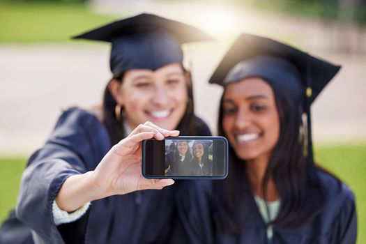 One more for the road. two attractive young female students taking selfies while celebrating on graduation day.