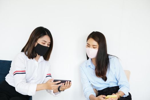 social distancing concept, Two women wearing masks and distancing while sitting on mobile phones following coronavirus social trend.