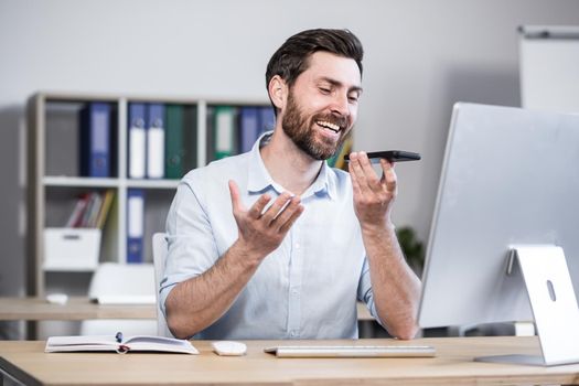 Young man with a beard, freelancer, manager, worker talking on a cell phone in the office