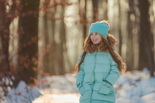 girl in the winter forest and turquoise-colored clothes