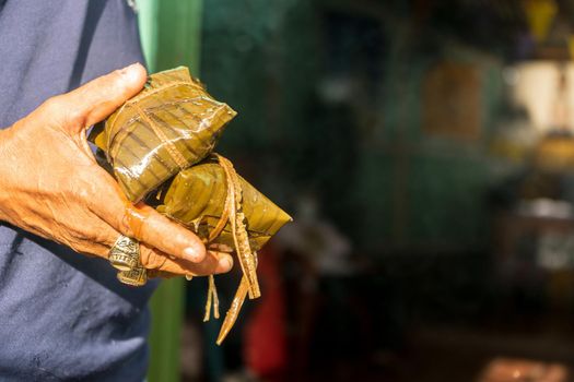 Hand of a Nicaraguan man holding two nacatamales
