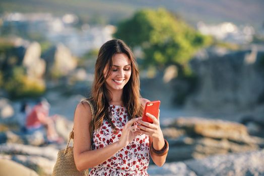 Beautiful woman using smartphone texting on beach at sunset