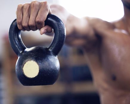 Heavy weights and hard work get big results. an unrecognisable man working out with a kettle bell at the gym.