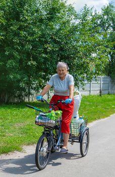 An old woman rides a bicycle. Selection focus.