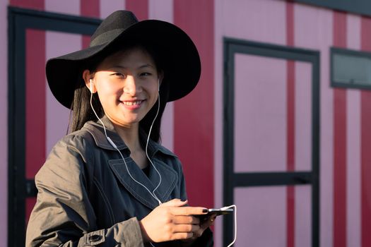 smiling asian woman with earphones listening music