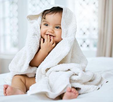 Im enjoying my daily pamper session. an adorable baby covered in a towel after bath time.