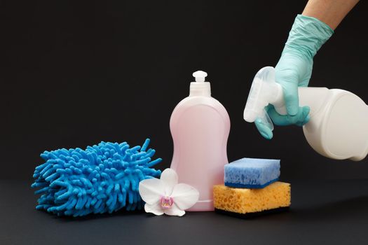 Bottle of detergent, a rag and sponges on the black background.