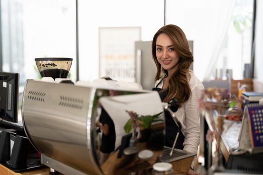 Attractive young beautiful asian barista with apron in coffee counter shop.