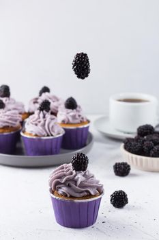 The blackberry falls on top of the cupcake. Floating food concept