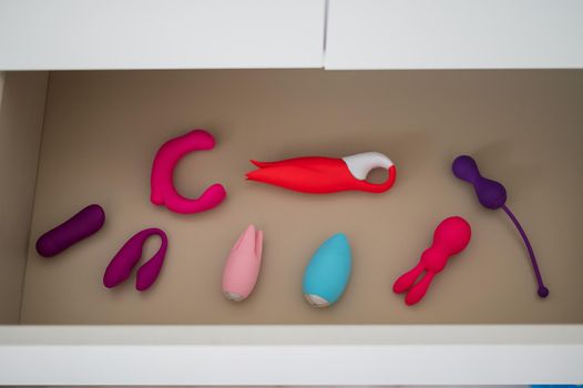 A collection of vibrators and dildos in a white chest of drawers. Private collection of sex toys.