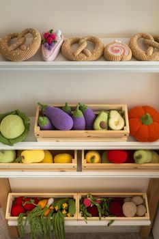 Artificial food in the children's kitchen. On the shelf are vegetables and fruits made of knitted threads