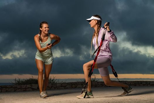 Girl fitness trainer trains girl outdoors near the sea.