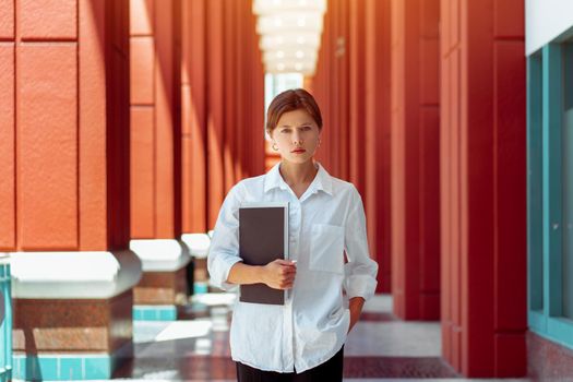 Businesswoman portrait. Caucasian female business person standing outdoor with business paper document holder.